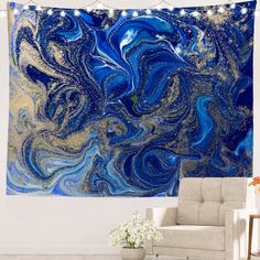 a blue and gold wall hanging in a living room with a white chair next to it