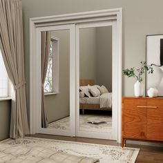 a bedroom with a bed, dresser and large mirror in the corner on the wall