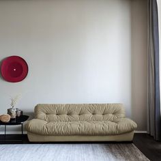 a living room with a couch, coffee table and red plate on the wall behind it