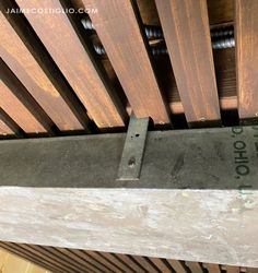 the bottom part of a wooden slatted ceiling with metal brackets and screws