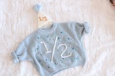 a blue sweater with the number twenty one on it and a party hat is laying next to an infant's head