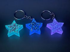 three glowing star shaped key chains on a black background