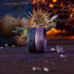 two purple rings sitting on top of a table next to some dried flowers and plants