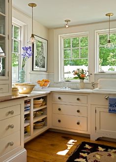 a kitchen filled with lots of white cabinets and counter top space next to a window