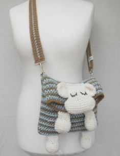 a crocheted purse with a stuffed animal hanging from it's side on a mannequin head