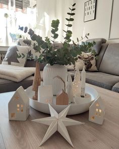 a table topped with white christmas decorations on top of a wooden table next to a couch