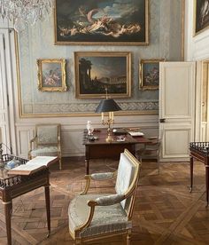 an ornate room with paintings on the wall and two desks in front of them