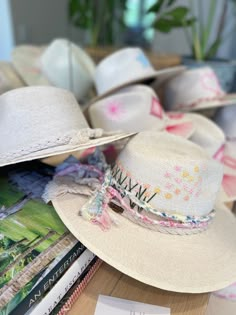 The wait is over! This hat is Ready to Ship and your order will be processed and shipped within 3-7 business days. Items with embroidery customization will be shipped within 2 weeks. White Palm Straw Hat with Pink and Yellow Floral and Star Design by Corazon Playero. Custom designed and hand made hats by artisans in San Jose Del Cabo, Mexico. These hats are one size fits most with an elastic band inside to add comfort and fit for all head sizes. Please note, all hats come with natural braid unle Embroidered Straw Hat, Leather Burning, San Jose Del Cabo Mexico, Hats Ideas, Rhinestone Jacket, Hat Decor, Hat Bar, Custom Made Hats, Cabo Mexico