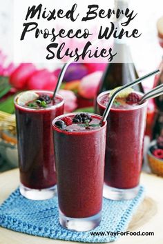 two glasses filled with mixed berry and raspberry wine slushies on top of a blue towel