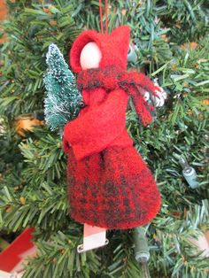 an ornament hanging from a christmas tree with a red scarf and hat on it