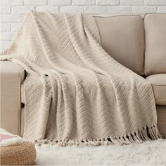 a couch with a blanket on top of it in front of a white brick wall