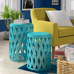 two blue and yellow stools in a living room next to a green chair with white pillows