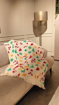 a couch with a blanket on top of it next to a lamp in a room