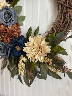 a wreath with flowers and leaves hanging on the wall