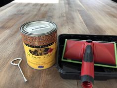 a can of paint next to a pair of scissors on a wooden table with other items