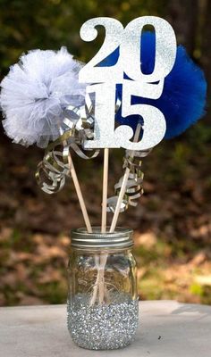 a mason jar filled with silver and blue flowers on top of a table next to a sign that says 25