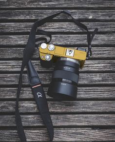 a camera with a strap attached to it sitting on a wooden table next to a bag