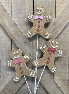 three decorated gingerbreads on sticks with pink bows