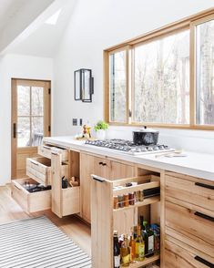 a kitchen with wooden cabinets and white counter tops in front of a large open window