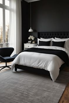 a black and white bedroom with a large bed in the center, two chairs next to it