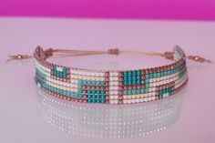 a beaded bracelet with blue and white beads on a pink surface, against a purple background