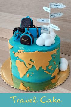 a blue and gold cake with luggage on it's top is sitting on a wooden table