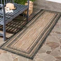 a bench sitting next to a rug on top of a stone floor