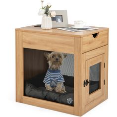 a small dog in a wooden crate with a blue and white shirt on it's chest