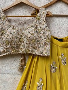 A three-piece mustard and beige mirror lehenga set from the Priti Sahni collection. This mustard georgette floral mirror embroidery butti lehenga with a heavy border of zari-pearl work detail is paired with a raw silk beige cutwork blouse with mirror, zardozi, resham work all over it. This outfit is completed with a mustard tulle net dupatta with scallop edging with highlights. Gold Sharara With Mirror Work In Georgette, Gold Palazzo Set With Mirror Work For Reception, Gold Palazzo Set With Dori Work For Party, Gold Dola Silk Palazzo Set With Mirror Work, Gold Lehenga With Mirror Work In Georgette, Gold Georgette Set With Mirror Work, Gold Palazzo Set With Mirror Work For Festivals, Festival Gold Palazzo Set With Mirror Work, Gold Palazzo Set With Mirror Work For Navratri