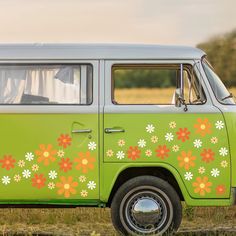 an old green van with flowers painted on it's side parked in a field