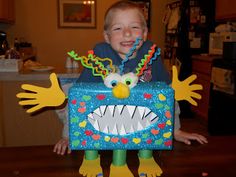 a young boy is holding up a box with an image of a monster on it