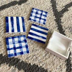 four blue and white coasters sitting on the floor next to an empty square box