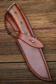 a knife is laying on top of a brown leather sheath with two holes in it