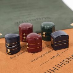 five different colored boxes sitting on top of a wooden table next to a book with writing