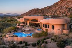 an aerial view of a house with a pool and mountains in the background