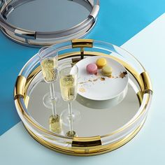 two champagne glasses are sitting on a tray next to an empty plate with desserts