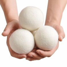 two hands holding three balls of white wool