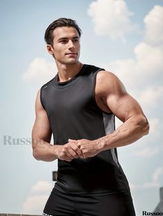 a man in black shirt and shorts standing next to a wall with his hands on his hips