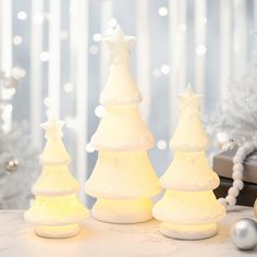 three white christmas trees sitting on top of a table