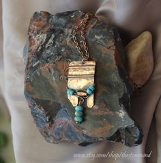 https://www.etsy.com/shop/thestonewind/ Hand-made in Northern California: unique, original design, hammered copper and gemstone jewelry.   Stone Wind "Wind Chime"  Beautiful hammered copper dangle pendant  necklace with light blue turquoise Magnesite stone round beads and Heishi beads. Unique and unusual gift for a man or for a woman. Turquoise is said to be a purification stone, dispelling negative energy to instill inner calm thereby promoting inner attunement and enhancing communication with Hammered Copper Jewelry, Copper Work, Minimalist Pendant, Necklace Stone, Unusual Gift, Jewelry Stone, Necklace Necklace, Heishi Beads, Copper Necklace