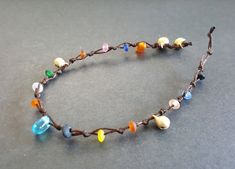 a bracelet made out of glass beads and brown leather cord with multicolored stones