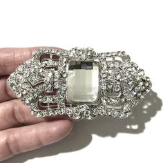 "A 1920s vintage style Gatsby wedding Art Deco bridal brooch sash pin featuring ornate geometric details made of clear swarovski crystals in silver rhodium or gold plated finish. This bridal brooch can be as a dress jewelry or on bridal bouquet. Brooch measures about 1 1/2\"(3.8cm) x 3\"(7.6cm) at its widest. View matching pieces or similar designs at https://etsy.me/2Mu6wjC and https://etsy.me/2tvK27M View all brooch pins at https://etsy.me/1eEBStU" Silver Art Deco Brooches For Wedding, Silver Art Deco Wedding Brooch, Silver Art Deco Wedding Brooches, Elegant Crystal-embellished Brooches For Weddings, Elegant Crystal-embellished Wedding Brooches, Elegant Crystal Embellished Brooches For Wedding, Art Deco Wedding Brooch Jewelry, Glamorous Silver Brooch For Wedding, Swarovski Crystal Dress