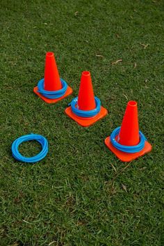 three orange cones and two blue rings on the grass