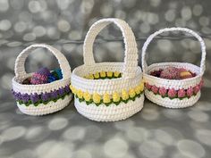 three white baskets with colorful crocheted handles