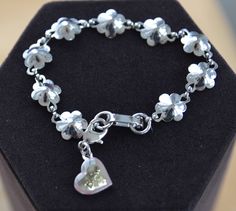 "Pretty and inspirational is this silver tone floral bracelet with a dangling heart charm. The charm reads \"Believe\" on one side, and \"Anything is Possible\" on the other. The charm has a lobster claw clasp and can be removed if you like. The bracelet measures 7-1/2\" and will fit an average wrist. It is in very good vintage condition and has a fold over clasp. The bracelet is lightweight." Adjustable Silver Heart Bracelet With Charms, Silver Engraved Heart Bracelet, Adjustable, Silver Sterling Charm Bracelet With Flower Charm, Silver Bracelets With Flower Charm For Mother's Day, Personalized Silver Flower Bracelets, Silver Personalized Flower Bracelet, Personalized Silver Flower Bracelet, Tout Est Possible, Floral Bracelet