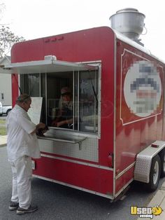 a man standing in front of a red food truck next to another man holding a piece of paper