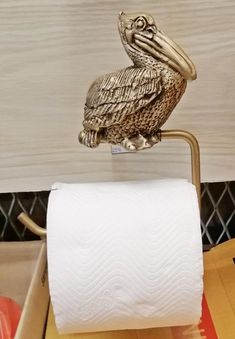 a golden pelican sitting on top of a roll of toilet paper