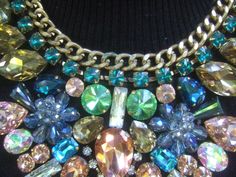 "Massive glittering crystal bib collar necklace The incredible huge scale bib style necklace is embellished with a collection of prong set glass crystals in a myriad of colors & shapes The top section of the necklace is designed with a rigid gilt metal chain framed with a wreath of emerald green color prong set crystals The lower section of the bib collar necklace is adorned with brilliant shimmering prong set crystals in a spectrum of colors that range from pink, pale & emerald green, a Rhinestone Jeweled Choker Necklace, Rhinestone Jewel Choker Necklace, Multicolor Crystal Necklaces For Parties, Glamorous Bib Necklace With Rhinestones, Party Jeweled Crystal Bib Necklaces, Costume Jewelry Bib Necklace With Jewels, Glamorous Rhinestone Bib Necklace, Jeweled Crystal Costume Jewelry Necklace, Party Costume Jewelry Bib Necklace With Rhinestones