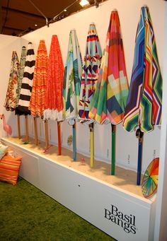 several colorful umbrellas are on display in a room with green carpeted flooring