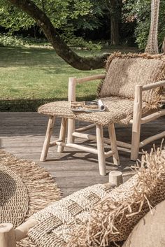 two wooden chairs sitting on top of a wooden deck next to a grass covered field